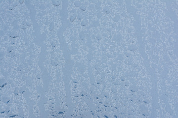 Big drops of rain on a car bonnet, the texture of paint is blue metallic, blue abstract bokeh background
