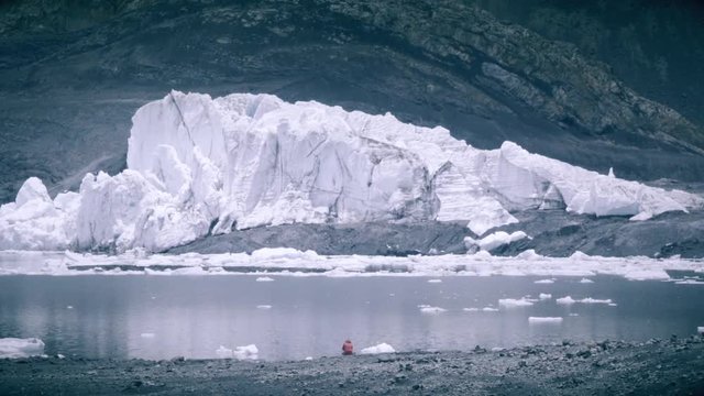 Woman contemplating glacier Pastoruri, pieces of ice floating on lagoon.