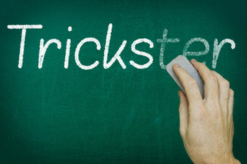 Hand erasing the word TRICKSTER written on blackboard