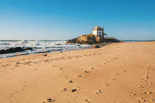 Ocean surf and Chapel Senhor da Pedra at Miramar Beach, near Porto, Portugal.