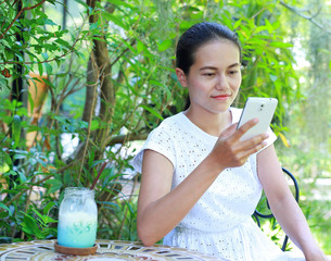 Young asian woman sitting at the outdoor cafe and using telephone