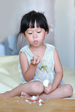 Little child girl eating boiled eggs at home.