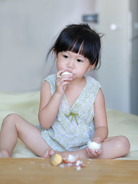 Little child girl eating boiled eggs at home.
