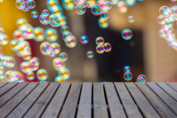 Empty wooden table or plank with bokeh of rainbow soap bubbles from the bubble blower on background...