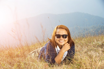 happy woman smile and lying on grass top mountain with sunny day, subject is soft focus and low key