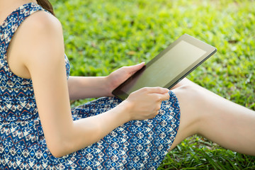 beauty asian woman using digital tablet sitting on grass