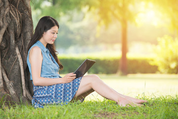 Fototapeta premium beauty asian woman using digital tablet sitting on grass