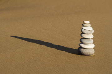 Fototapeta na wymiar Cairn of rounded rocks on wet beach sand