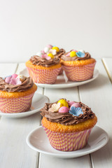 Easter Cupcakes Decorated with Easter Eggs and Wafer Flowers on White Wooden Table Vertical Selective Focus