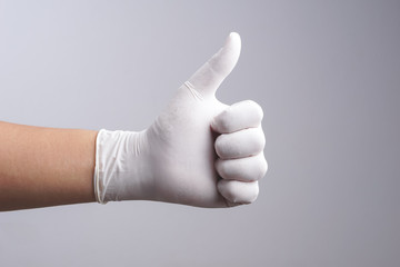 Hand wearing latex glove with thumb up gesture