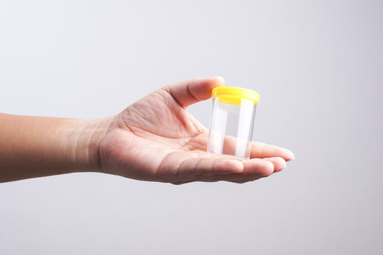 Hand holding empty urine plastic container