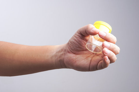 Hand holding empty urine plastic container