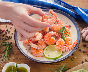 Woman hand with grilled shrimps.