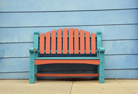 Tuerkisfarbige und braune Sitzbank vor einer hellblau 