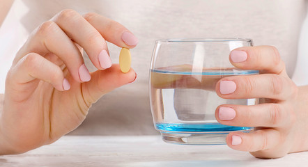 Woman holding glass  and pill. Healthcare and medical concept.