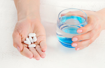 Young woman holding a glass of water and pills. Healthcare and medical concept. Top view