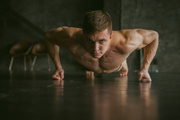 Young sexy male bodybuilder athlete with a bare torso. portrait of a studio of a light-skinned...