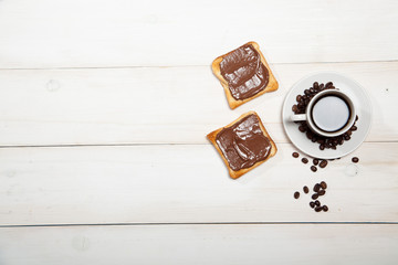 cup of coffee and toast with chocolate on a white wooden table