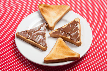 Toast with chocolate on a plate on a red table