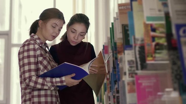 Two female students looking for necessary information in library books