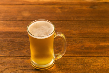 Glass of beer on wooden table in Golden Light