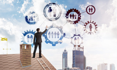 Businessman on house roof presenting teamwork and connection concept. Mixed media