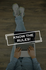 Young man sitting on floor with laptop and KNOW THE RULES! concept on screen