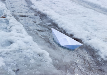 Paper boat in the stream of melt water
