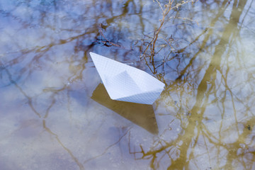 Paper boat in a puddle of melt water