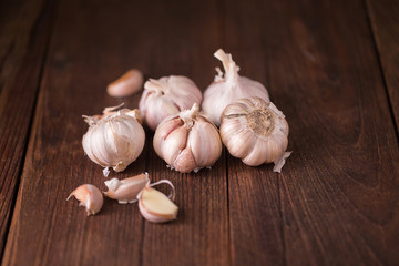Garlic and garlic press on rustic wooden board.