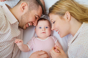 Happy family. Mother and father are lying on the bed with their baby.