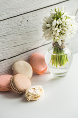 Fototapeta na wymiar Colorful macaroons with flowers on a beautiful wooden background