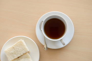 Top view of a cup of hot tea with sandwich on wooden table