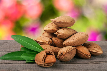 heap of almonds in their skins and peeled with leaf isolated on white background