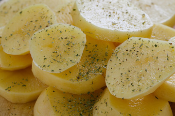Raw peeled potatoes with spices, butter slices ready to be roasted as background