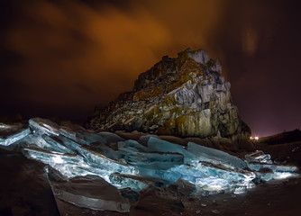 Illuminated hummocks of ice in front of a rock shaman on an olkhon