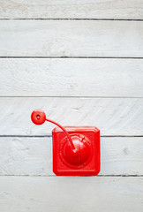 Red old vintage mechanical coffee grinder on white wooden surface.