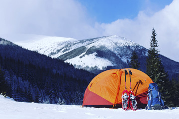 Winter hiking in the mountains on snowshoes with a backpack and tent.