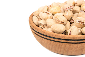 Part of a wooden bowl with pistachios on a white background, close-up