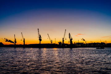 Fototapeta premium Hamburger Hafen mit Hafenkränen beim Sonnenuntergang