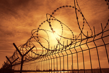 Prison barbed wire fence at sunset
