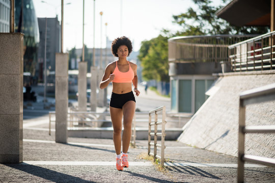 Athletic teenager girl running on city street