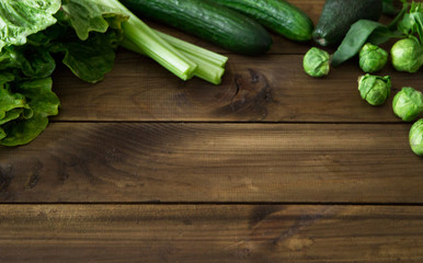 Products containing folic acid - B9 vitamin . Green vegetables on wooden background. Celery, avocado, Brussels sprouts, basil, cucumber, romaine salad