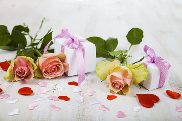 Pink roses,  gift and hearts on a wooden background.