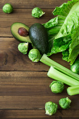 Products containing folic acid - B9 vitamin . Green vegetables on wooden background. Celery, avocado, Brussels sprouts, romaine salad