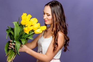 Young beautiful woman holding a bouquet of yellow tulips. Spring.