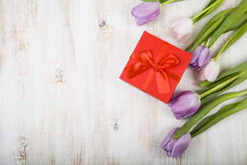 Bouquet of tulips and a gift on a wooden background.