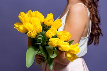 Young beautiful woman holding a bouquet of yellow tulips. Spring.