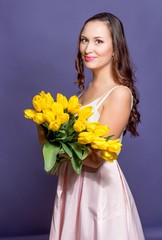 Young beautiful woman holding a bouquet of yellow tulips. Spring.
