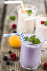 Three glasses with smoothies  or yogurt with fresh berries on a wooden table.